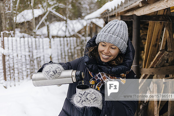 Portrait of happy woman using thermo flask in winter