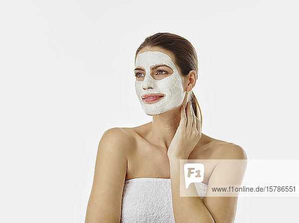 Portrait of smiling woman with beauty mask in front of white background