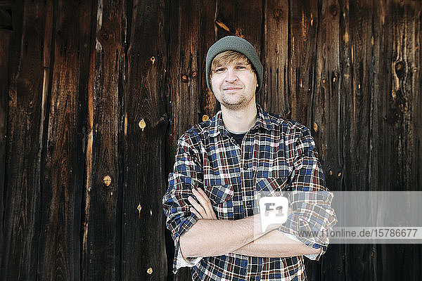 Porträt eines selbstbewussten Mannes mit Wollhut an Holzwand