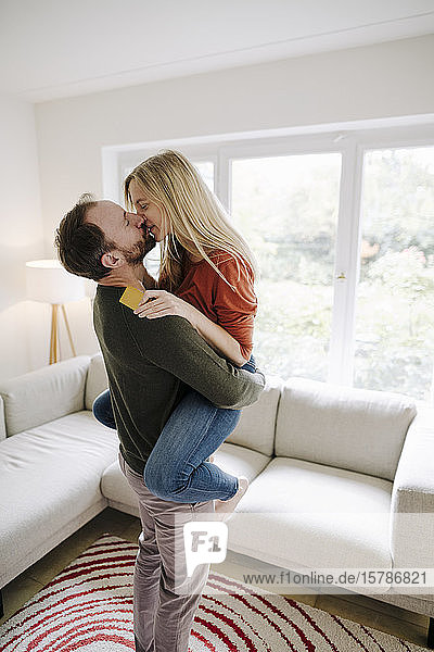 Happy couple standing at home  kissing  holding credit card