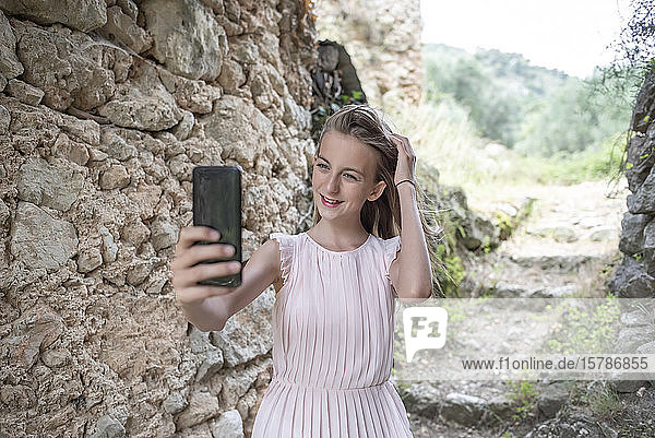 Mädchen  das sich neben einer alten Steinmauer eingenistet hat  Frankreich