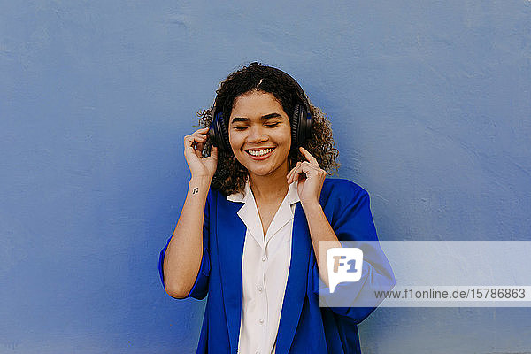 Porträt einer lächelnden Frau  die mit Kopfhörern Musik hört