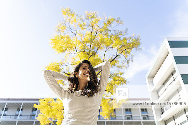Glückliche junge Frau im Freien an einem Baum