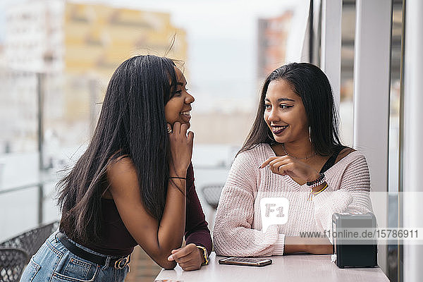 Zwei glückliche junge Frauen im Dachcafé