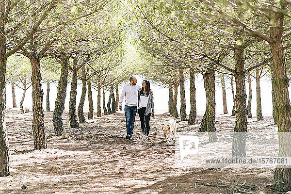 Couple walking with their dog in a park