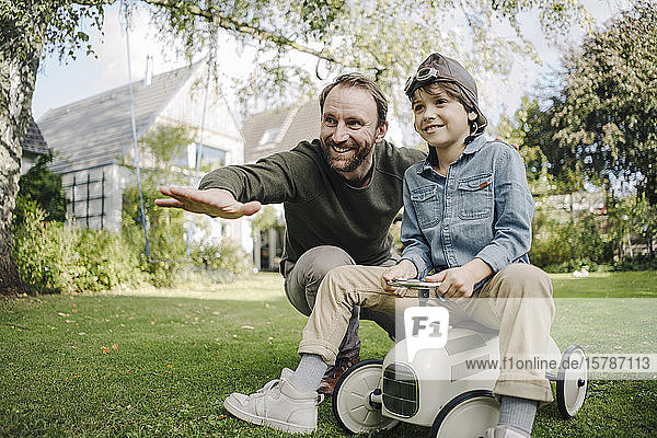 Vater und Sohn spielen mit einem Spielzeugauto im Garten