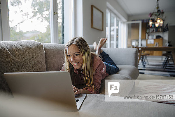 Woman lying on couch  using laptop