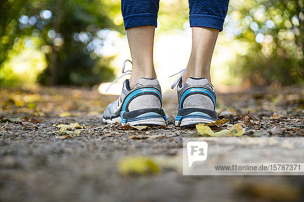 Close-up of spotive woman standing on autumnal footpath