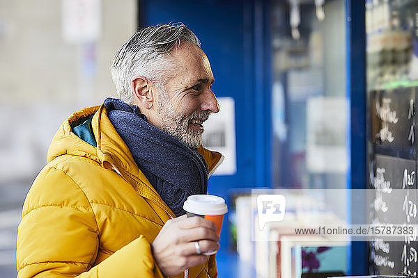 Smiling mature man at a stall with takeaway coffee