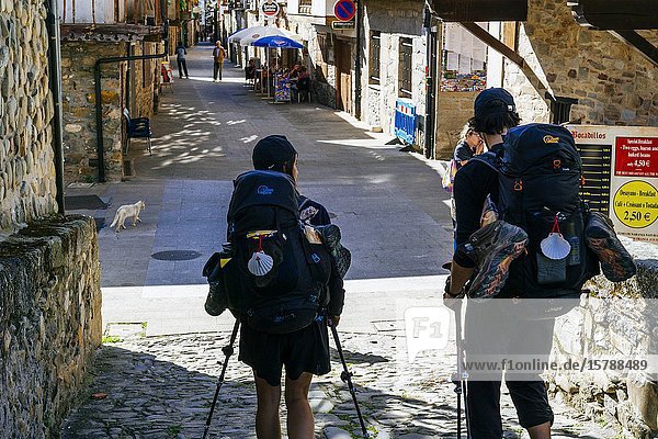 Couple of pilgrims accessing the historic center of Molinaseca through Calle Real. French Way  Way of St. James. Molinaseca  El Bierzo Leon  Castile and Leon  Spain  Europe.