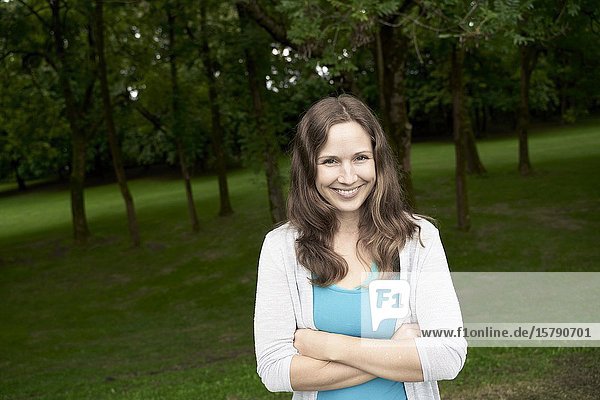 Portrait of woman in park  with arms crossed. Munich  Germany.