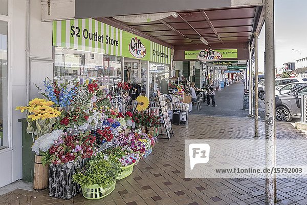 THAMES  NEW ZEALAND - November 07 2019: cityscape of historical village with fake flowers on sale under commercial buildings covered walkway on main street  shot in bright late spring light on november 07 2019 at Thames  Coromandel  North Island  New Zealand.