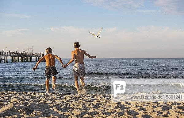 Two young people run into the water at the Baltic Sea beach  Kühlungsborn  Mecklenburg-Western Pomerania  Germany  Europe
