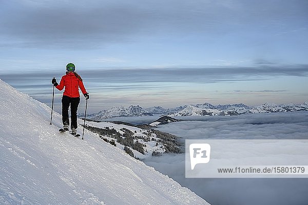 Skifahrer auf der Skipiste stehend  im Hintergrund Bergpanorama über der Wolkendecke  SkiWelt Wilder Kaiser  Brixen im Thale  Tirol  Österreich  Europa