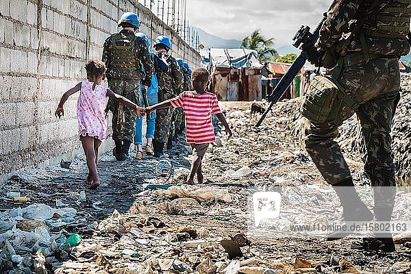 Zwei Kinder und UN-Patrouille  blaue Helme  gehen durch Müll  Cité Soleil  Port-au-Prince  Ouest  Haiti  Mittelamerika