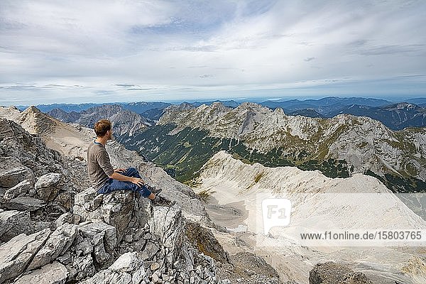 Wanderer auf dem Gipfel der Birkkarspitze sitzend  Blick auf das Schlauchkar und Karwendeltal mit der östlichen Karwendelspitze  Hinterautal-Vomper-Kette  Karwendel  Tirol  Österreich  Europa