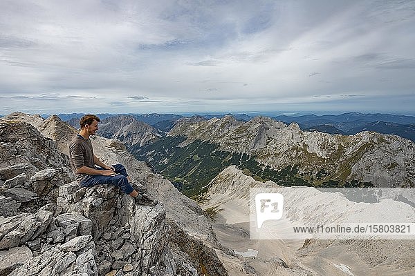 Wanderer auf dem Gipfel der Birkkarspitze sitzend  Blick auf das Schlauchkar und Karwendeltal mit der östlichen Karwendelspitze  Hinterautal-Vomper-Kette  Karwendel  Tirol  Österreich  Europa