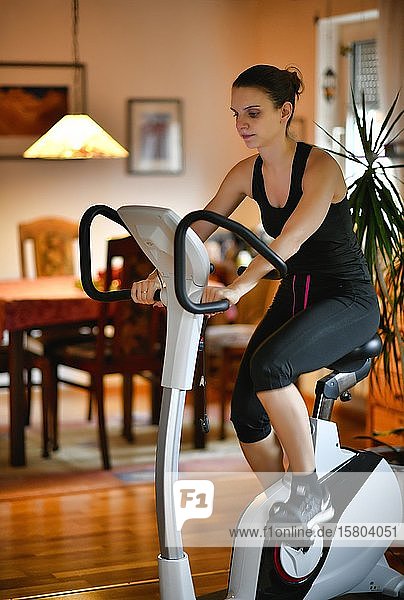 Young woman doing sports at home on an ergometer  Stuttgart  Baden-Württemberg  Germany  Europe