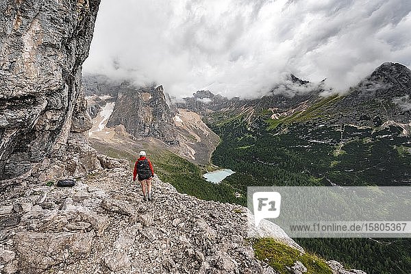 Junge Frau  Wanderin auf einem Klettersteig  Via ferrata Vandelli  Sorapiss-Rundweg  Berge mit niedrigen Wolken  Dolomiten  Belluno  Italien  Europa