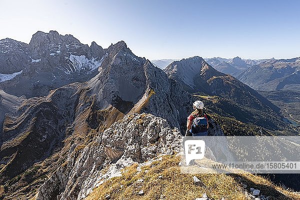 Junge Frau  Bergsteigerin mit Kletterhelm  Blick auf Berglandschaft  Wanderung zur Ehrwalder Sonnenspitze  hinter Grünstein und westlicher Marienbergspitze  Ehrwald  Mieminger Kette  Tirol  Österreich  Europa