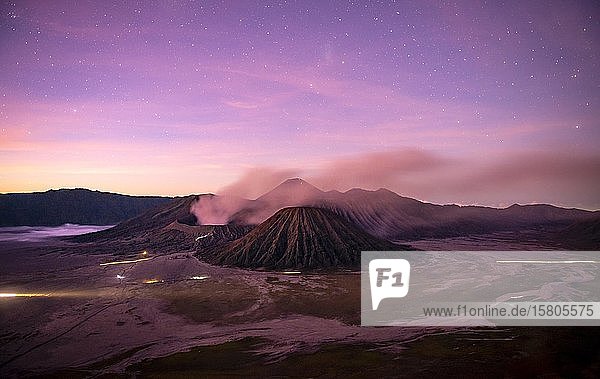 Volcanic landscape at sunrise with starry sky  smoking volcano Gunung Bromo  with Mt. Batok  Mt. Kursi  Mt. Gunung Semeru  National Park Bromo-Tengger-Semeru  Java  Indonesia  Asia