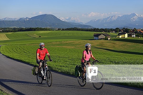 Couple with electric bikes at Sulzberg  Obertrum  in the background the Berchtesgaden Alps and the Dachstein Mountains  Salzburg Lakeland  Salzburger Land  Austria  Europe