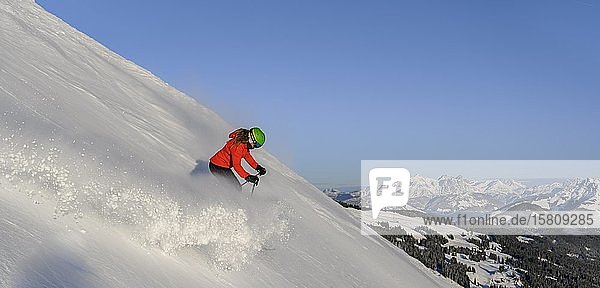 Skier going down steep slope  black piste  blue sky  mountains behind  SkiWelt Wilder Kaiser  Brixen im Thale  Tyrol  Austria  Europe