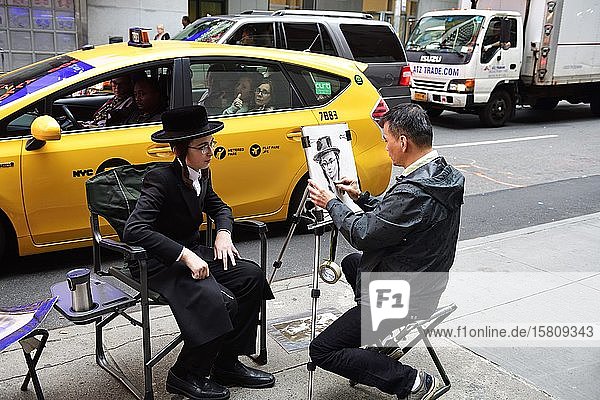 Ein jüdisch-orthodoxer Junge mit Schläfenlocken und Hut wird am Times Square von einem Straßenmaler porträtiert  Manhattan  New York City  New York State  USA  Nordamerika