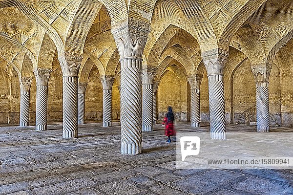 Iranische Frau geht durch die Gebetshalle mit Shabestan-Säulen  Vakil-Moschee  Shiraz  Provinz Fars  Iran  Asien