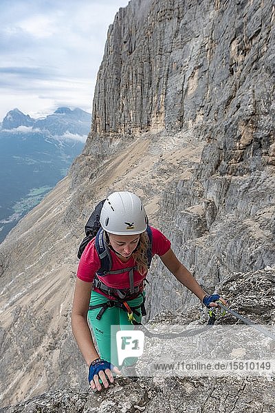 Young woman  hiker secured by a steel rope while climbing a rock face  Via ferrata Francesco Berti  Sorapiss circuit  Dolomites  Belluno  Italy  Europe