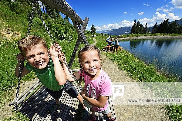 Family playing during a hike at the storage lake at the middle station Hohe Salve Hopfgarten Brixental Kitzbüheler Alps Tyrol Austria Europe