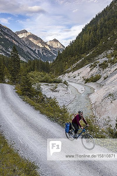Cyclist  mountain biker cycles on gravel road  Karwendelbach  Karwendel valley  way to the Karwendelhaus  Tyrol  Austria  Europe