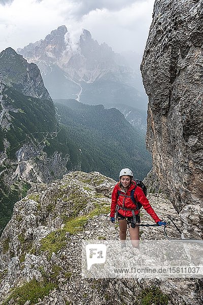 Young woman  hiker climbing a via ferrata Vandelli  Sorapiss circuit  mountains with low clouds  Dolomites  Belluno  Italy  Europe