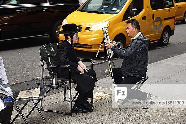 Ein jüdisch-orthodoxer Junge mit Schläfenlocken und Hut wird am Times Square von einem Straßenmaler porträtiert Manhattan New York City New York State USA Nordamerika