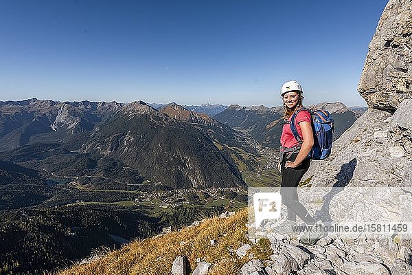 Young woman  mountaineer with climbing helmet looking at mountain landscape  hike to Ehrwalder Sonnenspitze  behind Grünstein and western Marienbergspitze  Ehrwald  Mieminger Kette  Tyrol  Austria  Europe