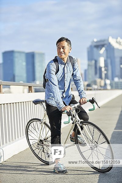 Mature Japanese man with bike downtown Osaka  Japan