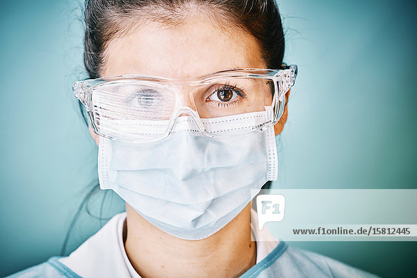 Ärztin mit Schutzbrille und Mundschutz blickt in Kamera