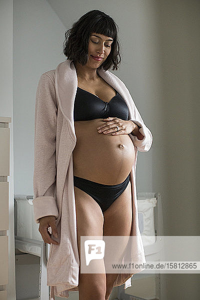 Pregnant woman in bra and panties touching stomach