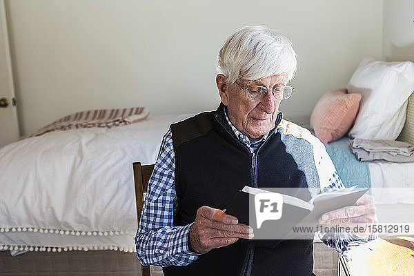 Senior man reading a book in his bedroom