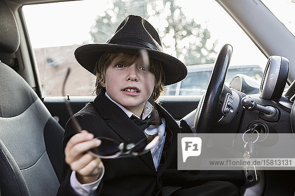 Ein sechsjähriger Junge sitzt im Auto und hält ein Lenkrad