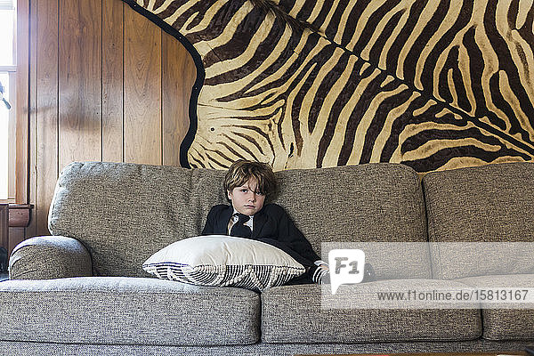 A six year old boy sitting on sofa
