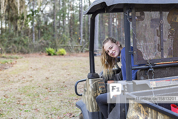 A teenage girl in an all terrain vehicle  a buggy  looking out.