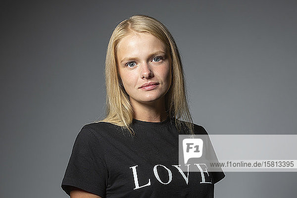 Porträt zuversichtlich  junge Frau in der Liebe T-Shirt auf grauem Hintergrund
