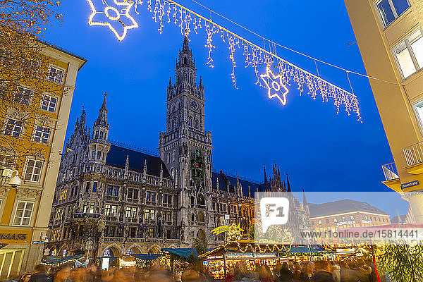 Blick auf das Neue Rathaus und den belebten Weihnachtsmarkt auf dem Marienplatz in der Abenddämmerung  München  Bayern  Deutschland  Europa