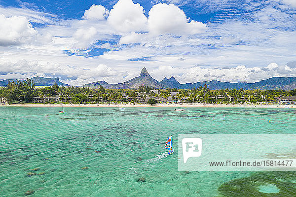 Aerial view by drone of windsurfer in the lagoon facing Flic en Flac beach and Piton de la Petite Riviere Noire mountain Black River Mauritius Indian Ocean Africa
