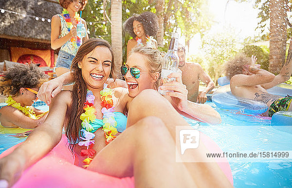 Porträt begeisterte  lachende junge Frauen Freunde trinken und spielen im Sommer Schwimmbad