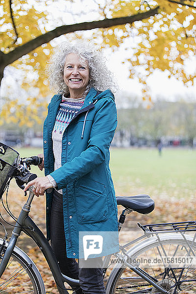 Portrait smiling  confident senior woman bike riding in autumn park