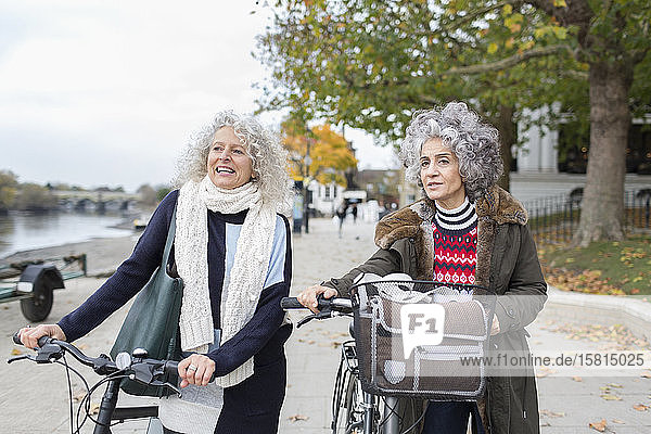 Aktive Seniorinnen  die mit dem Fahrrad im Herbstpark unterwegs sind