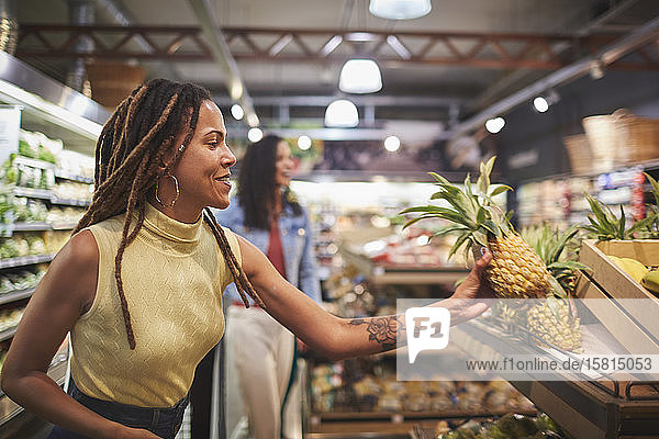 Frau beim Einkaufen von Ananas in der Gemüseabteilung eines Supermarkts