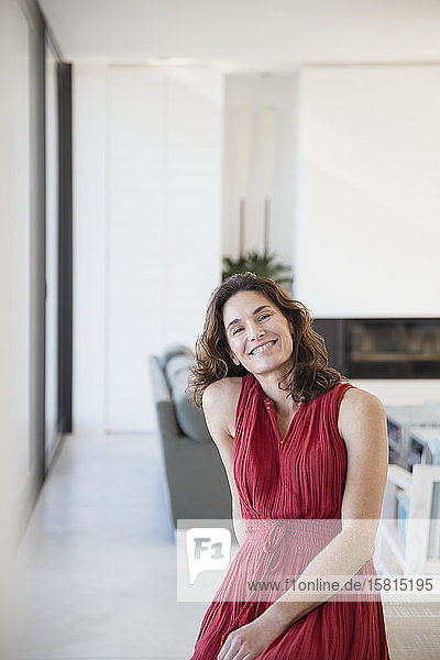 Portrait smiling  confident brunette woman in red dress at home